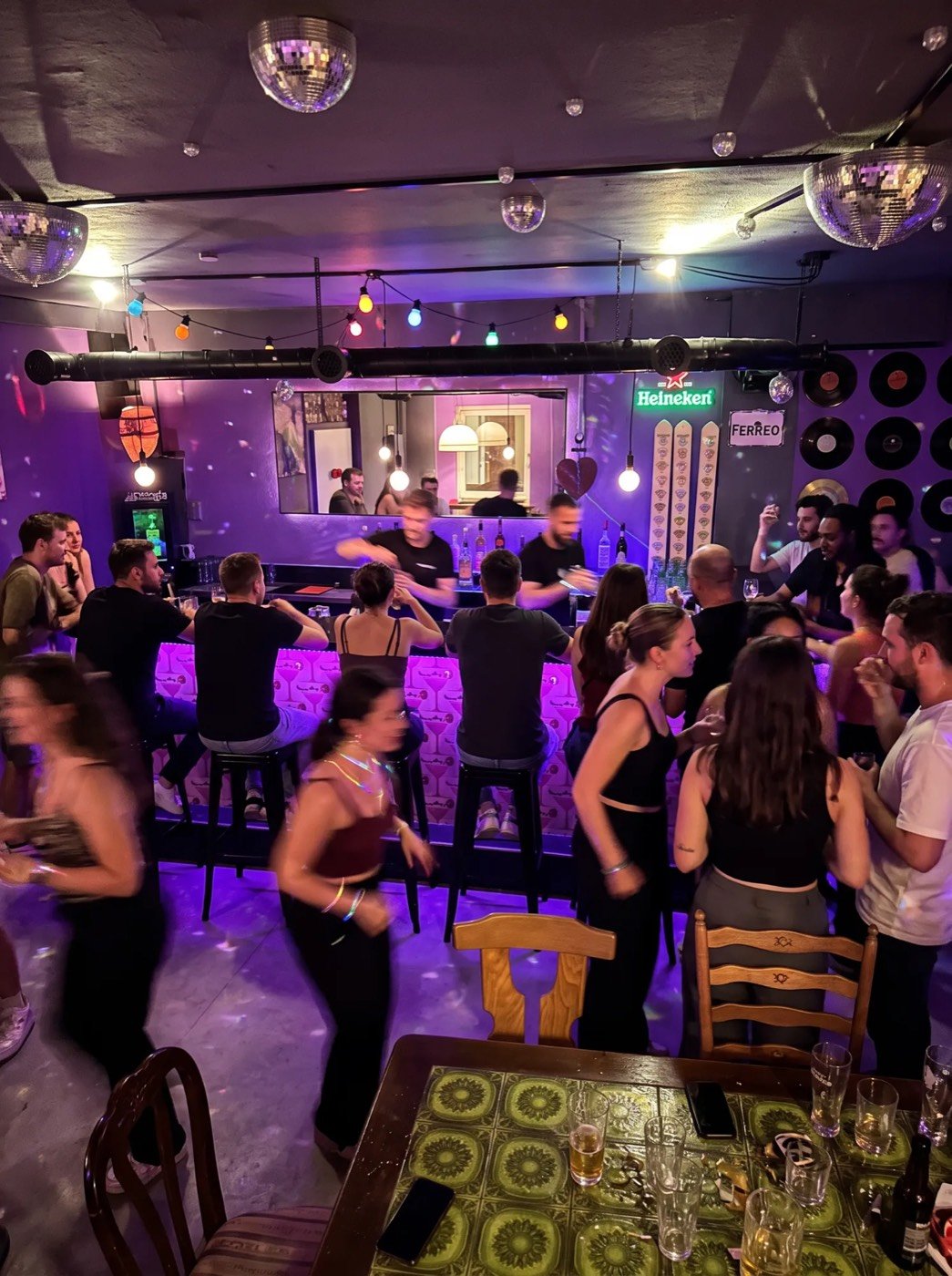 Gäste am beleuchteten Tresen der Boogie Bar Stade unter Discokugeln